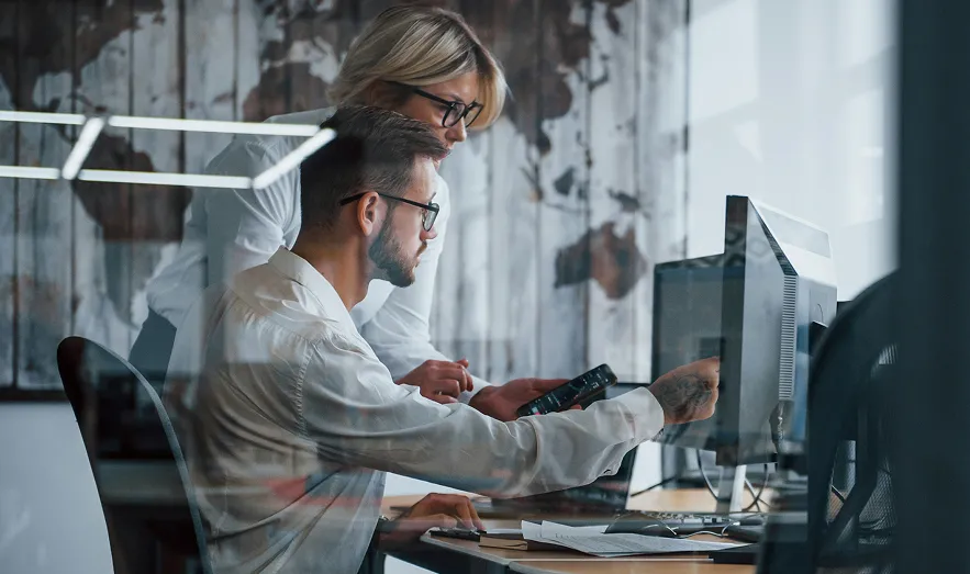 Professionals collaborating around a computer in a modern office.